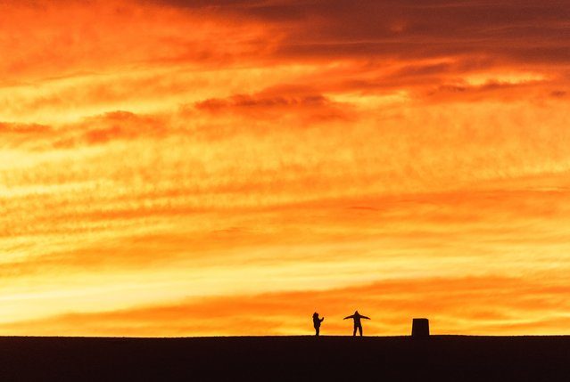 A couple are silhouetted against a spectacular sunset over the Isle of Portland in Dorset, UK on December 27, 2023. (Photo by West Bay Photography/BNPS)