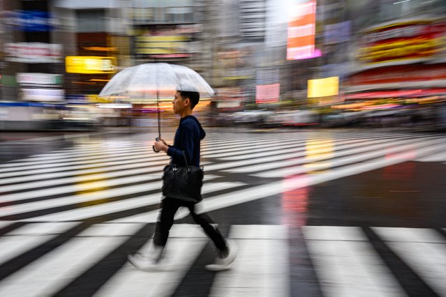 A man uses an umbrella to shelter from the rain while crossing a street in Tokyo's Shinjuku district on June 18, 2024. (Photo by Philip Fong/AFP Photo)