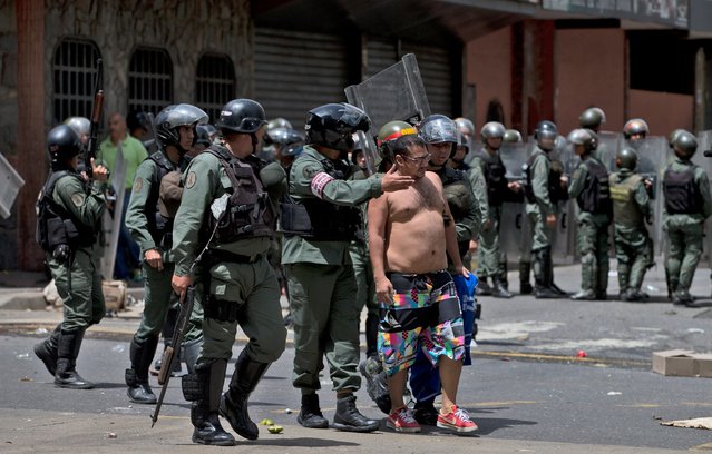 Bolivarian National Guards detain a man during a protest by people demanding food, a few blocks from Miraflores presidential palace in Caracas, Venezuela, Thursday, June 2, 2016. Venezuela is seeing rising frustration with widespread food shortages and triple-digit inflation. (Photo by Fernando Llano/AP Photo)