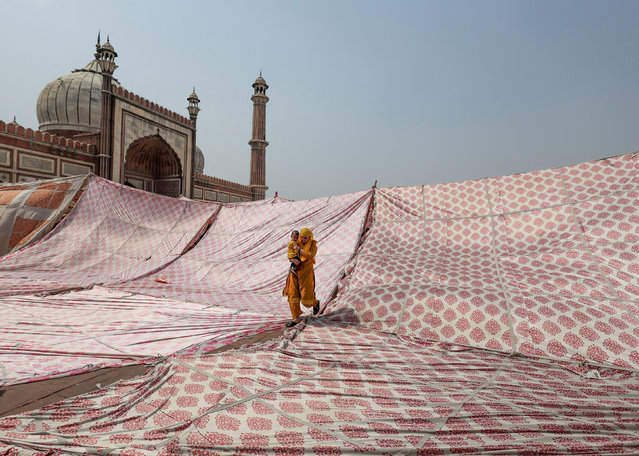 A Muslim woman with a child leaves after offering prayers during Jumat-ul-Vida or the last Friday of the holy fasting month of Ramadan, at Jama Masjid in the old quarters of Delhi, India, April 29, 2022. (Photo by Anushree Fadnavis/Reuters)