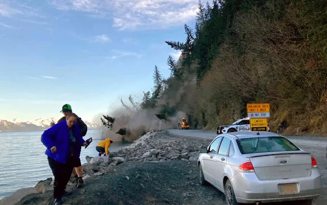 People run from a landslide just outside the downtown area of Seward, Alaska, May 7, 2022. There were no reported injuries in the landslide, which the city estimates could take up to two weeks to clear. (Photo by Josh Gray via AP Photo)