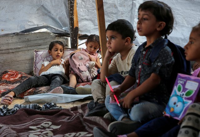 Palestinian students attend a class in a tent set up on the rubble of the house of teacher Israa Abu Mustafa, as war disrupts a new school year in Khan Younis, in the southern Gaza Strip on September 4, 2024. (Photo by Hatem Khaled/Reuters)