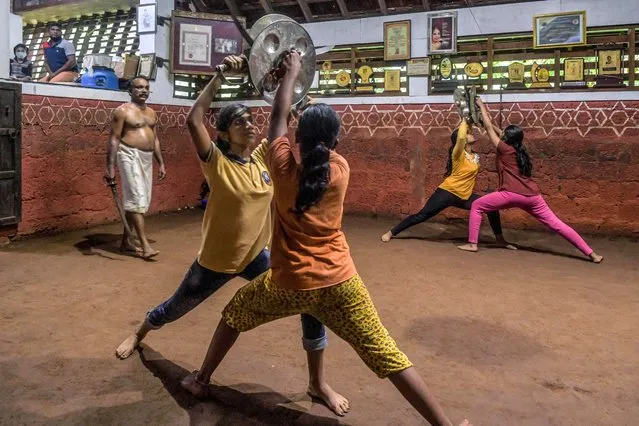 This picture taken on September 14, 2021 shows Sajeev Kumar (L) practitioner and teacher of “Kalaripayattu”, a traditional martial art originated in Kerala, training students at his family-run Kadathanadan Kalari Sangam school in Vatakara in the Kozhikode district of the state of Kerala. Deftly parrying her 60-year-old son with a two-handed bamboo cane, Meenakshi Amma belies her 78 years with her prowess at kalari, thought to be India's oldest martial art. The great-grandmother in Kerala in southern India has been a driving force in the revival of kalaripayattu, as the ancient practice is also known, and in encouraging girls to take it up. (Photo by Manjunath Kiran/AFP Photo)