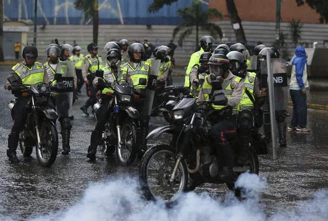 Police ride in to clear a protest by bank employees in Caracas, Venezuela, Wednesday, June 28, 2017. (Photo by Fernando Llano/AP Photo)