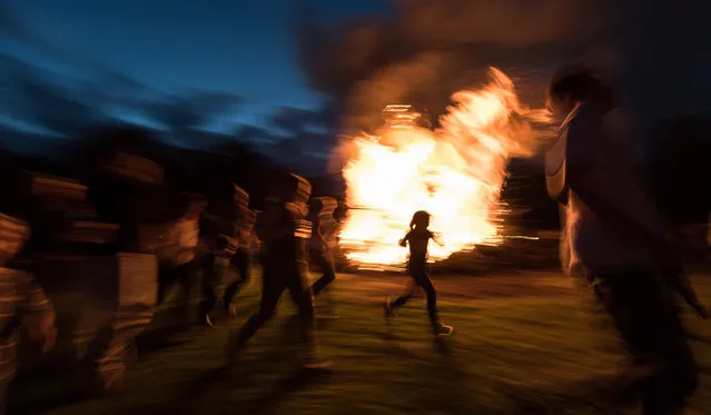 People dance at the Midsummer Fire on the Mundenhof in Freiburg, Germany, 21 June 2016. The solstice is celebrated on the longest day and the shortest night of beginning of summer in the year. (Photo by Patrick Seeger/EPA)