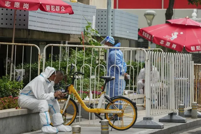 Workers in protective gear on duty watch at barricaded neighborhood that has been locked down as part of COVID-19 controls in Beijing, Monday, June 13, 2022. (Photo by Andy Wong/AP Photo)