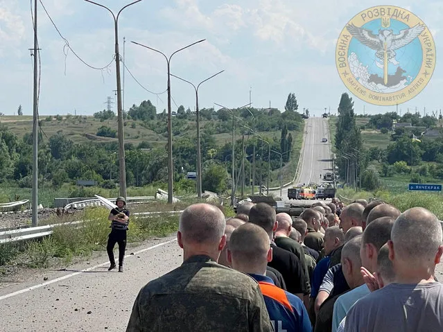 A man with a white flag walks along the road during an exchange of prisoners, as Russia's attack on Ukraine continues, at a location given as Zaporizhzhia region, Ukraine, in this handout photo released on June 29, 2022. (Photo by Ukraine's Military Intelligence/Handout via Reuters)