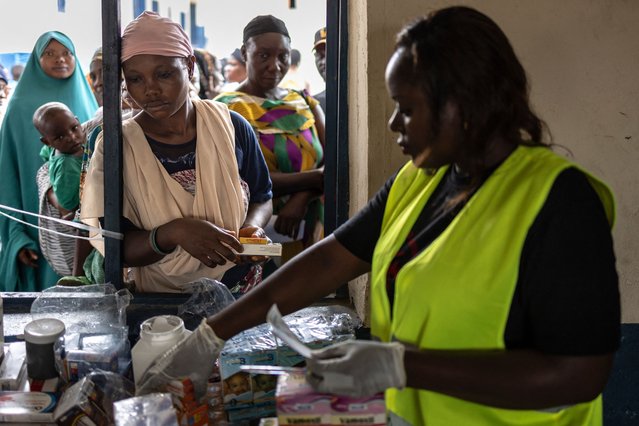 A health worker gives medicine to a woman in St. Luke school, that is used as a shelter for internally displaced persons from the floods, in Lokoja on October 22, 2024. Human-caused climate change worsened floods that have killed hundreds of people and displaced millions in Cameroon, Chad, Niger, Nigeria and Sudan this year, according to a study published on October 23, 2024. (Photo by Olympia de Maismont/AFP Photo)