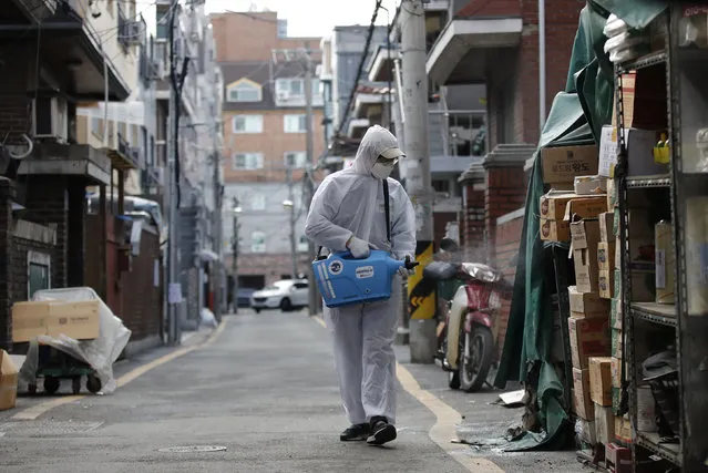 A worker wearing a protective suit sprays disinfectant as a precaution against new virus at a market in Seoul, South Korea, Wednesday, February 26, 2020. The number of new virus cases in South Korea jumped again Wednesday and the first U.S. military soldier tested positive, with his infection and many others connected to a southeastern city where the outbreak has clustered. (Photo by Lee Jin-man/AP Photo)