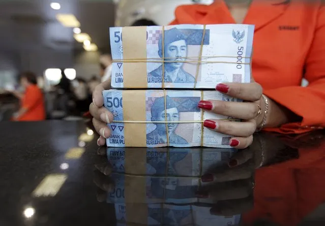 A teller prepares Indonesian rupiah for a customer at a money changer in Jakarta, Indonesia, August 24, 2015. Emerging Asian currencies fell to their lowest in years on Monday as a rout in Chinese stocks accelerated a flight from risky assets on intensifying fears of slowing global growth. Indonesia's rupiah slid to its weakest since the Asian financial crisis 17 years ago as falling commodity prices clouded its exports and economic prospects. (Photo by Nyimas Laula/Reuters)