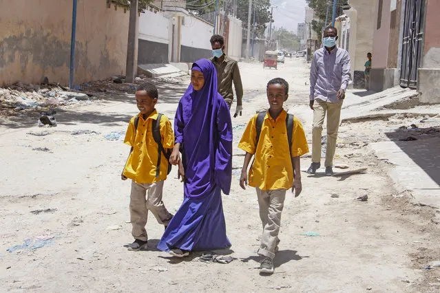 Somali schoolchildren walk home, while other people wear surgical masks, after the government announced the closure of schools and universities and banned large gatherings, following the announcement on Monday of the country's first case of the new coronavirus, in the capital Mogadishu, Somalia Wednesday, March 18, 2020. (Photo by Farah Abdi Warsameh/AP Photo)