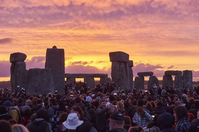 This file photo taken on June 21, 2015 shows revellers watching the sunrise as they celebrate the pagan festival of Summer Solstice at Stonehenge in Wiltshire, southern England on June 21, 2015. Years of protests from druids and archaeologists have failed to derail plans for a new road tunnel near Britain's Stone Age site of Stonehenge, which received final approval from the government on September 12. (Photo by Niklas Halle'n/AFP Photo)