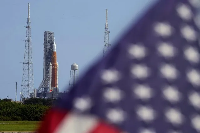 An American flag flies in the breeze as NASA's new moon rocket sits on Launch Pad 39-B after being scrubbed at the Kennedy Space Center Saturday, September 3, 2022, in Cape Canaveral, Fla. This is scheduled to be the first flight of NASA's 21st-century moon-exploration program, named Artemis after Apollo's mythological twin sister. (Photo by Chris O'Meara/AP Photo)