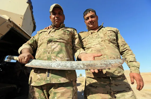 An Iraqi soldier holds a sword which Iraqi army said belonged to the Islamic State militants, in Zumar, Nineveh province, Iraq October 18, 2017. (Photo by Ari Jalal/Reuters)