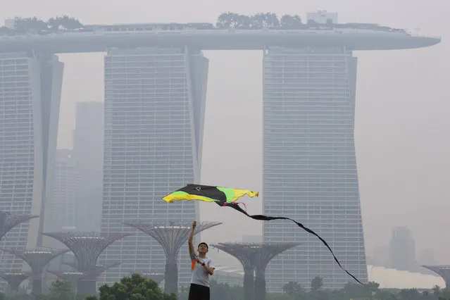 A man flies a kite during a hazy day in Singapore, Thursday, September 10, 2015. Air pollution in Singapore reached its highest level in a year on Thursday as smog from Indonesian forest fires shrouded the island nation in a veil of gray, irking tourists and alarming authorities with hours left before general elections. (Photo by Ng Han Guan/AP Photo)
