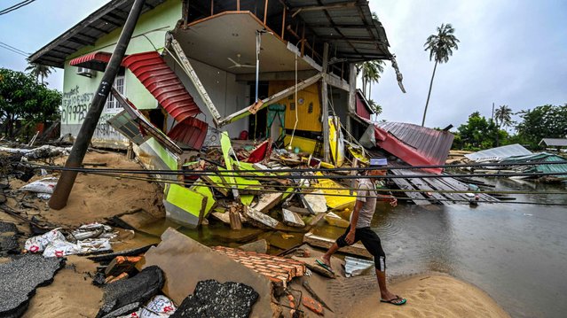 A man walks past a home damaged by flood waters in Tumpat, Malaysia's Kelantan state, on December 4, 2024. Malaysian disaster officials said on December 3 that more than 94,000 people were yet to return to their homes after being evacuated due to the floods, with five people reported dead. (Photo by Mohd Rasfan/AFP Photo)