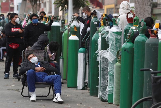 People wearing masks amid the spread of the new coronavirus wait for hours, some for 10 hours, to refill their oxygen cylinders at a shop that sells oxygen in Callao, Peru, Monday, June 8, 2020. Long neglected hospitals in Peru and other parts of Latin America are reporting shortages of oxygen as they confront the COVID-19 pandemic. (Photo by Martin Mejia/AP Photo)