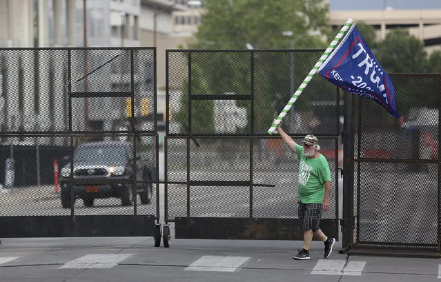 Mike Pellerin waves a Donald Trump campaign flag near a barricade in downtown Tulsa, Okla., ahead of President Donald Trump's Saturday's campaign rally Friday, June 19, 2020. (Photo by Mike Simons/Tulsa World via AP Photo)