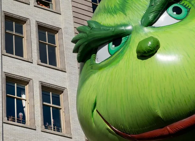 The Grinch balloon passes by windows of a building on Central Park West during Macy's Thanksgiving Day Parade in New York Thursday, November 23, 2017. (Photo by Craig Ruttle/AP Photo)