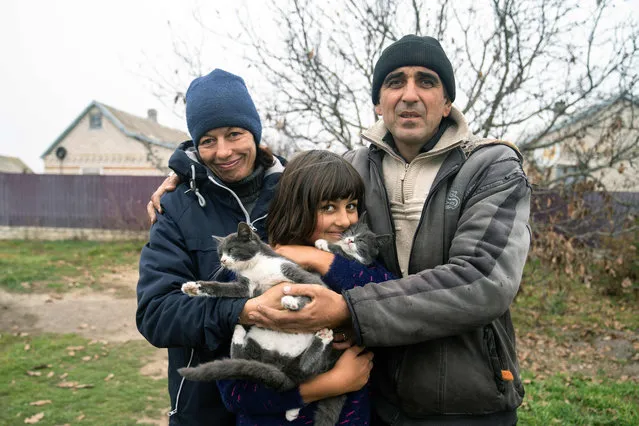 44-year Viktor Galak (R), poses with his 43-year wife Svitlana (L) and their 10-year-old daughter Anna (C), in the liberated village of Pravdyne, Kherson region, on November 12, 2022, amid the Russian invasion of Ukraine. On November 11, Russia said it had withdrawn more than 30,000 troops in the southern region, with Ukrainian President Volodymyr Zelensky declaring Kherson "ours" as residents reacted with joy and jubilation. (Photo by AFP Photo/Stringer)