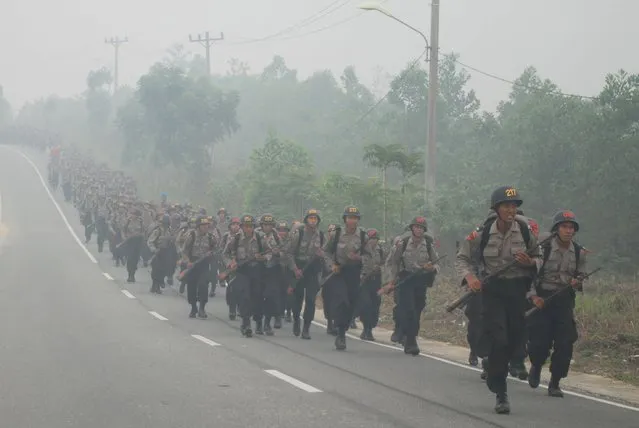 Students of State Police School (SPN) run amid haze while attending a physical exercise in Pekanbaru, Indonesia Riau province, September 30, 2015 in this picture taken by Antara Foto. Indonesia has sent nearly 21,000 personnel to fight forest fires raging in its northern islands, the disaster management agency said on Tuesday, but smoke cloaks much of the region with pollution readings in the "very unhealthy" region in neighbouring Singapore. (Photo by Rony Muharrman/Reuters/Antara Foto)