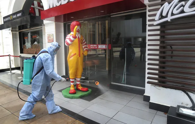 An employee disinfects a closed mall in Mumbai, Thursday, July 30, 2020. Malls and market complexes will reopen on Aug. 5. However theaters, food courts and gyms will remain closed. (Photo by Rafiq Maqbool/AP Photo)