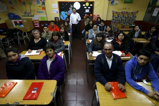 Teacher Guillermo Valenzuela poses for a picture with students of primary grade who are attending a night school for adults at Laura Vicuna school, in a popular neighbourhood of Santiago, September 10, 2015. (Photo by Ivan Alvarado/Reuters)