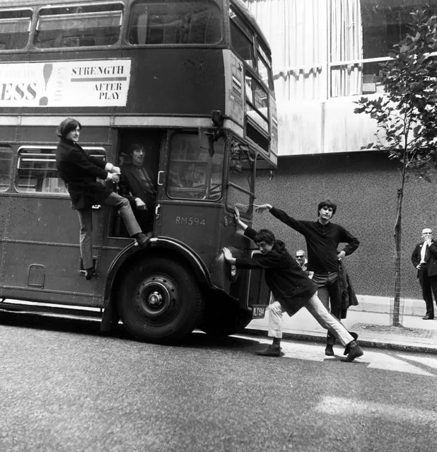 The four-member British rock group the Kinks, from Muswell Hill, joke around with a double decker bus on a London street, England, September 7, 1964.  Posing from left are, Dave Davies; Mick Avory, in driver's seat; Pete Quaife and Ray Davies. (Photo by AP Photo)
