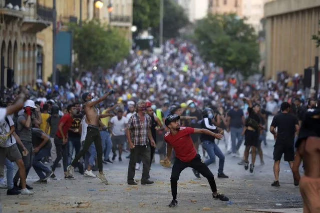 People throw stones during anti-government protest following Tuesday's massive explosion which devastated Beirut, Lebanon, Sunday, August 9. 2020. (Photo by Hassan Ammar/AP Photo)