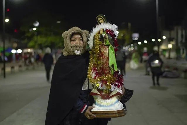 Victoria Hernandez poses for a photo with her Guadalupe statue outside the Basilica of Guadalupe in Mexico City, early Monday, December 12, 2022. Devotees of the Virgin of Guadalupe make the pilgrimage for her Dec. 12 feast day, the anniversary of one of several apparitions of the Virgin Mary witnessed by an Indigenous Mexican man named Juan Diego in 1531. (Photo by Aurea Del Rosario/AP Photo)