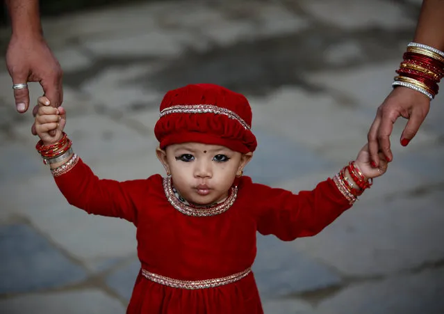 A young girl, holding the hands of her parents, pouts while being photographed during the Kumari Puja festival in Kathmandu, Nepal September 14, 2016. (Photo by Navesh Chitrakar/Reuters)