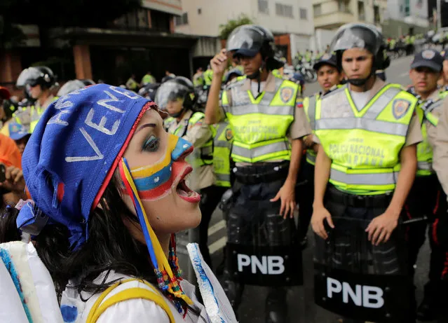 A supporter of Venezuela's opposition faces police officers who are blocking a street, as she takes part in a rally to demand a referendum to remove Venezuela's President Nicolas Maduro, in Caracas, Venezuela, September 16, 2016. (Photo by Henry Romero/Reuters)