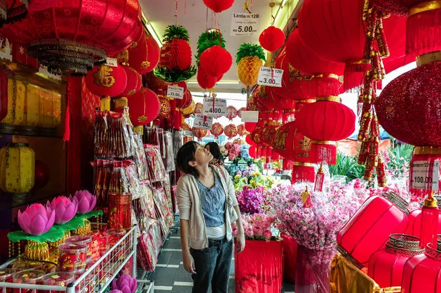 Customers look at the Chinese lanterns and decorations ahead of the Lunar New Year celebrations in Kuala Lumpur' s Chinatown on January 26, 2018. As the Year of the Dog approaches, some shops run by ethnic Chinese in Malaysia are keeping canine models inside instead of displaying them prominently to avoid causing offence in the Muslim- majority country. (Photo by Mohd Rasfan/AFP Photo)