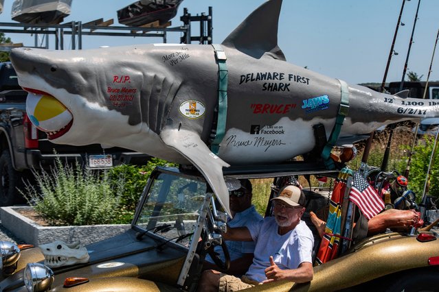 A person drives around the island in a dune buggy with a great white shark attached to the roof during the Jaws 50th Anniversary celebration in Oak Bluffs, Massachusetts on June 21, 2025. (Photo by Joseph Prezioso/AFP Photo)