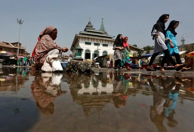 Girls are reflected in a puddle while walking on the street amidst the coronavirus disease (COVID-19) outbreak in Srinagar, September 14, 2020. (Photo by Danish Ismail/Reuters)