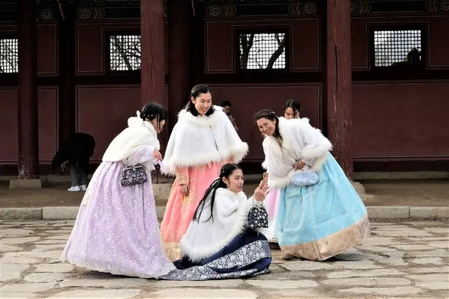 People wearing South Korean traditional “Hanbok” costume watch a smartphone as they visit to celebrate the Lunar New Year at the Gyeongbok Palace, the main royal palace during the Joseon Dynasty, and one of South Korea's well known landmarks in Seoul, South Korea, Sunday, January 22, 2023. (Photo by Ahn Young-joon/AP Photo)