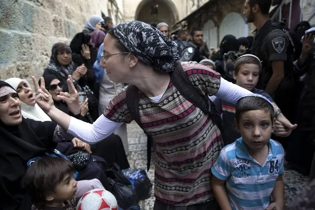 An Israeli woman (C) and a Palestinian woman gesture at one another during a protest by Palestinian women against Jewish visitors to the compound known to Muslims as Noble Sanctuary and to Jews as Temple Mount in Jerusalem's Old City in this October 14, 2014 file photo. The Palestinian women were singing and chanting in Arabic while heavily armed Israeli border police looked on and occasionally pushed them back to make way for Jewish worshipers going to the Western Wall. (Photo and caption by Finbarr O'Reilly/Reuters)