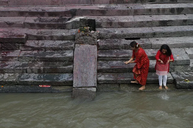 Nepalese devotees collect water from the Bagmati river to perform rituals as the Pashupati temple was closed as a precautionary measure against the spread of the coronavirus in Kathmandu, Nepal, Friday, August 21, 2020. The old palace courtyard packed with hundreds of thousands of people each year during the festival season is deserted, the temples are locked and all public celebrations are banned by the government to curb the coronavirus. (Photo by Niranjan Shrestha/AP Photo)