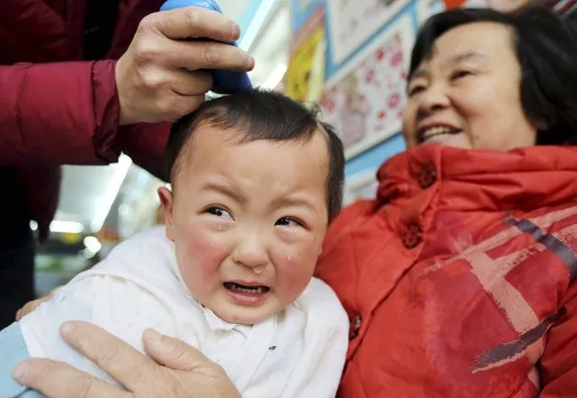 A child cries while getting a haircut at a barber shop in Huaibei, Anhui province, March 13, 2013. According to traditional Chinese beliefs, getting a haircut on the second day of the second month of the Chinese lunar calendar, which falls on March 13 this year, will bring good luck. (Photo by Reuters/China Daily)