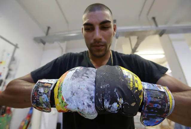 In this photo taken on Tuesday, September 6, 2016 Omar Hassan wears his gloves in his studio in Milan, Italy. (Photo by Antonio Calanni/AP Photo)