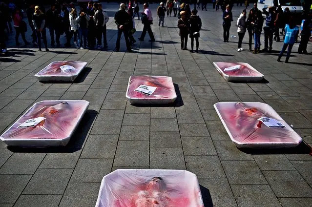Animal rights activists from the group “Animal Equality” lie wrapped in meat packaging as they stage a protest during “Day Without Meat” event in Barcelona, Spain, on March 20, 2013. (Photo by Emilio Morenatti/Associated Press)