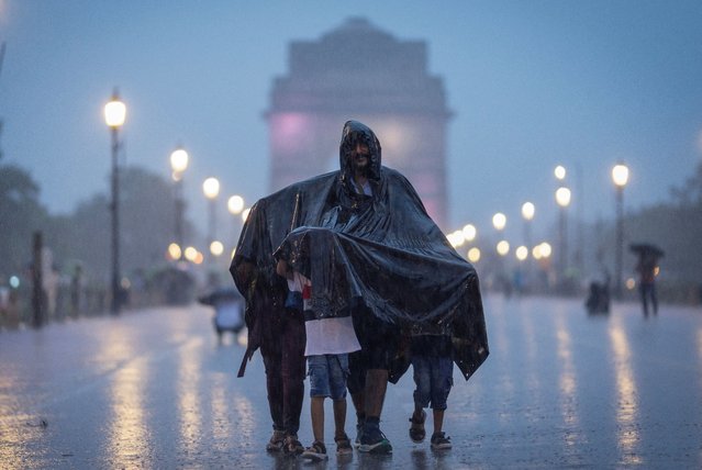 A family uses a plastic sheet to protect themselves during heavy rains in New Delhi, India on July 14, 2025. (Photo by Adnan Abidi/Reuters)
