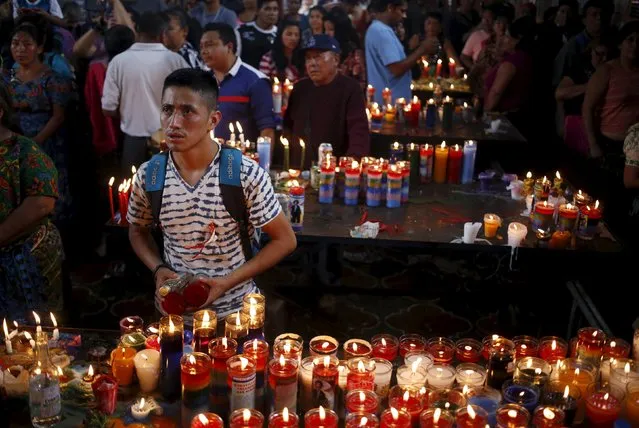 A man holds candles in a church in honor of San Simon in Chimaltenango, around 62 km (39 miles), from Guatemala City, October 28, 2015. (Photo by Jorge Dan Lopez/Reuters)