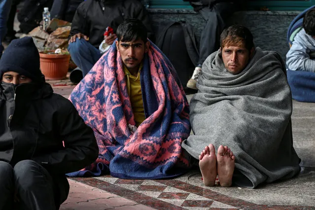 Refugees and migrants try to warm themselves as they take a break at a petrol station before abandoning their trek to the Hungarian border, in the town of Indjija, Serbia October 5, 2016. (Photo by Marko Djurica/Reuters)