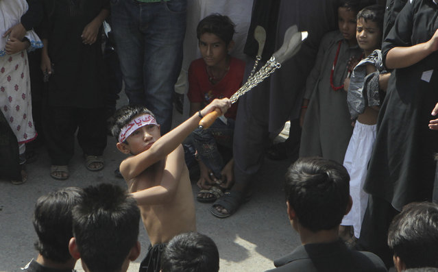 A Pakistani Shiite boy flagellates himself during a Muharram processions in Lahore, Pakistan, Tuesday, October 11, 2016. (Photo by K.M. Chaudhry/AP Photo)