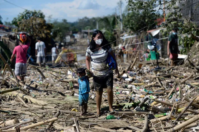 A woman and a child walk on debris brought by the flood following Typhoon Vamco, in Rodriguez, Rizal province, Philippines, November 13, 2020. (Photo by Lisa Marie David/Reuters)