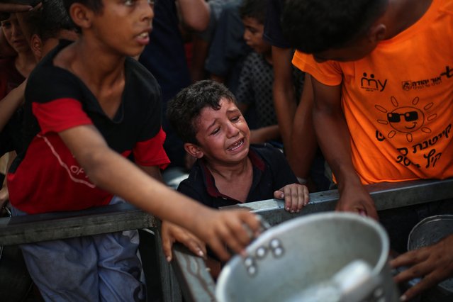 A Palestinian boy cries while waiting to receive a hot meal from a charity kitchen in the Nuseirat refugee camp in the Israel-besieged Gaza Strip on September 4, 2025, where the UN has declared famine after nearly two years of war. (Photo by Eyad Baba/AFP Photo)