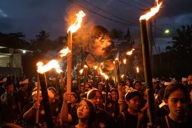 Balinese young women hold bamboo torches during the ogoh-ogoh parade on the eve of Nyepi, the Balinese Hindu Day of Silence that marks the arrival of the new Saka lunar year on March 20, 2023 in Tegalalang Village, Gianyar, Bali, Indonesia. (Photo by Agung Parameswara/Getty Images)