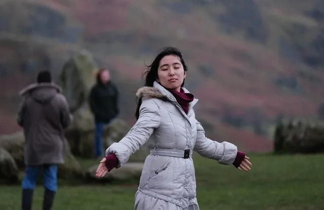 A woman closes her eyes and leans into the wind during the evening of the Winter Solstice at the Castlerigg Stone circle on December 21, 2014 in Keswick, England. The circle dates back over 4,000 years to neolithic times and is a popular meeting place for people from all over Britain who come to celebrate both the winter and summer solstices with the beautiful Cumbrian fells as a backdrop. (Photo by Ian Forsyth/Getty Images)