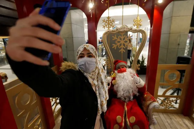 A young woman takes a selfie with a man dressed as a Santa Claus ahead of Christmas at a mall in Amman, Jordan December 15, 2020. (Photo by Muhammad Hamed/Reuters)